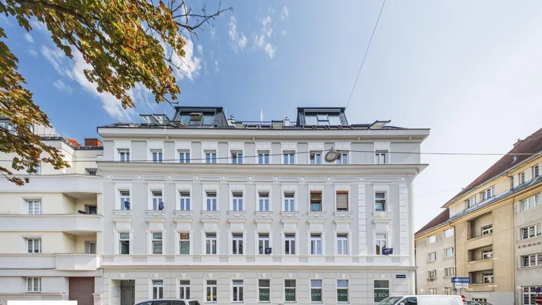 Historisches Gebäude mit modernisierten Dachgauben und klassischer Fassade an einer Stadtstraße.