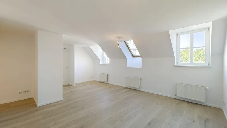 Heller Dachbodenraum mit Holzboden, Dachfenster und schrägen Wänden, ideal als Wohn- oder Schlafbereich.