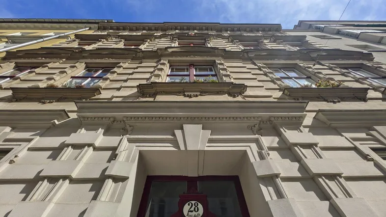 Historische Fassade eines Altbaus mit dekorativen Elementen und blauer Himmel.
