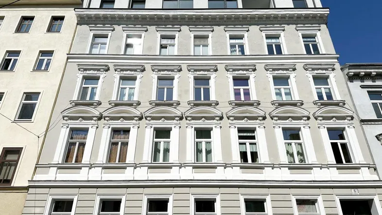 Historisches Mehrfamilienhaus mit klassischer Fassade und modernem Dachausbau in der Stadt.