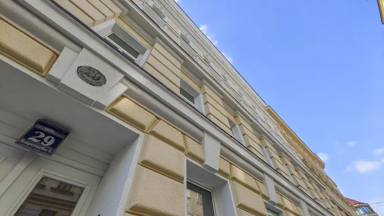 Blick auf die historische Fassade eines Altbaus mit dekorativen Elementen und blauer Himmel.
