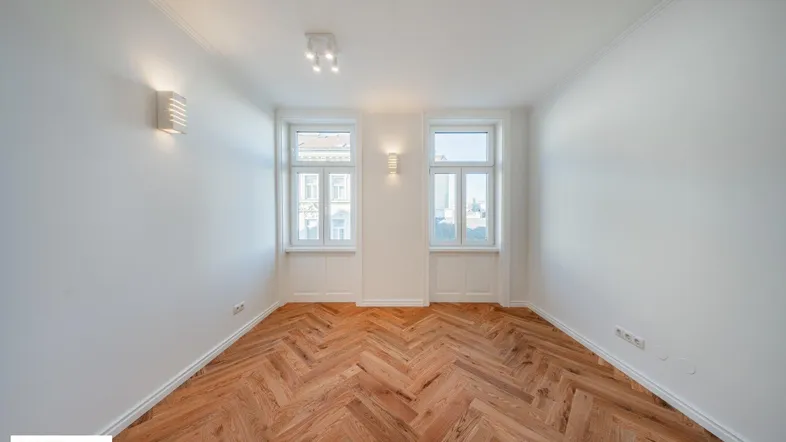 Helles Zimmer mit Fischgrätparkettboden und weißen Wänden, bereit zur individuellen Gestaltung.