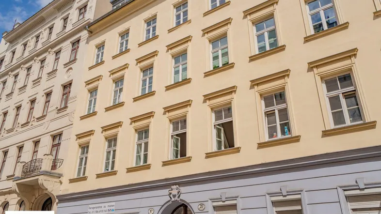 Historische Fassade eines Mehrfamilienhauses mit zahlreichen Fenstern und klassischer Architektur in der Stadt.
