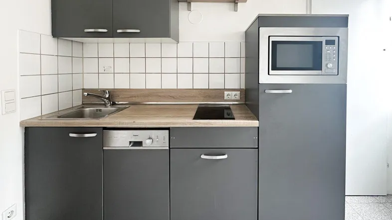 Moderne Küchenzeile in Grau mit integriertem Geschirrspüler und Mikrowelle.