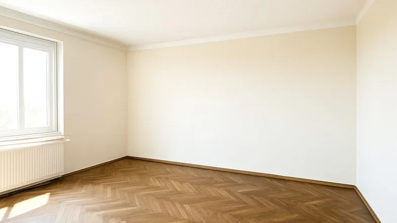 Helles Zimmer mit Fischgrätparkett und großem Fenster, ideal als Wohn- oder Schlafzimmer.
