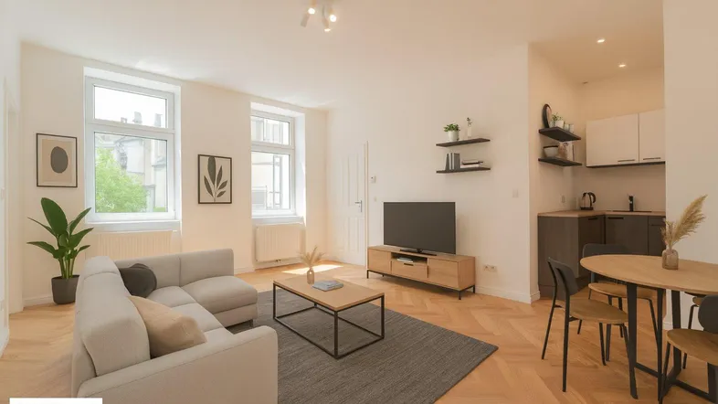 Helles Wohnzimmer mit offener Küchenzeile, Esstisch und Fischgrätparkettboden.