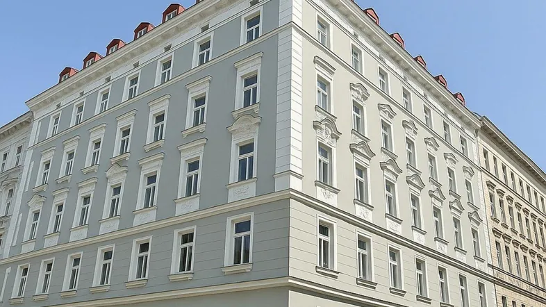 Mehrstöckiges Gebäude mit klassischer Fassade und vielen Fenstern unter blauem Himmel.