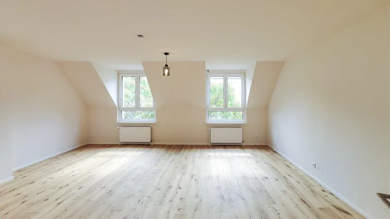 Heller Wohnraum im Dachgeschoss mit neuem Parkettboden und schrägen Wänden.