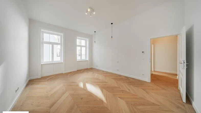 Helles Wohnzimmer mit Fischgrätparkettboden und weißen Wänden, bereit zur individuellen Gestaltung.