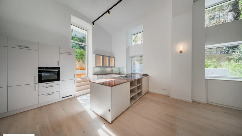 Helle, moderne offene Küche mit Kochinsel, hohen Decken und großen Fenstern.