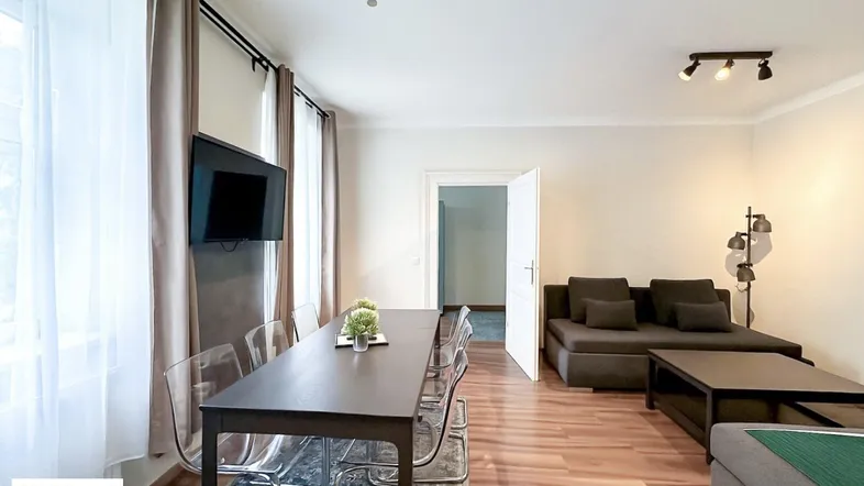 Geräumiger Wohn-Essbereich mit modernem Esstisch, bequemer Couch und Holzboden.