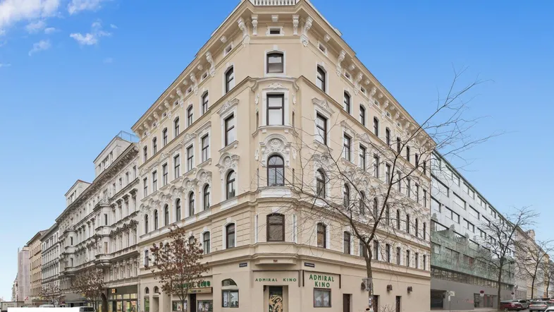 Großes Eckgebäude mit klassischer Architektur und vielen Fenstern in städtischer Umgebung.
