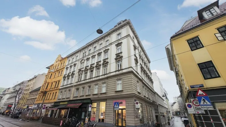 Historisches Eckgebäude in urbaner Umgebung mit Geschäften im Erdgeschoss und klassischer Fassade.