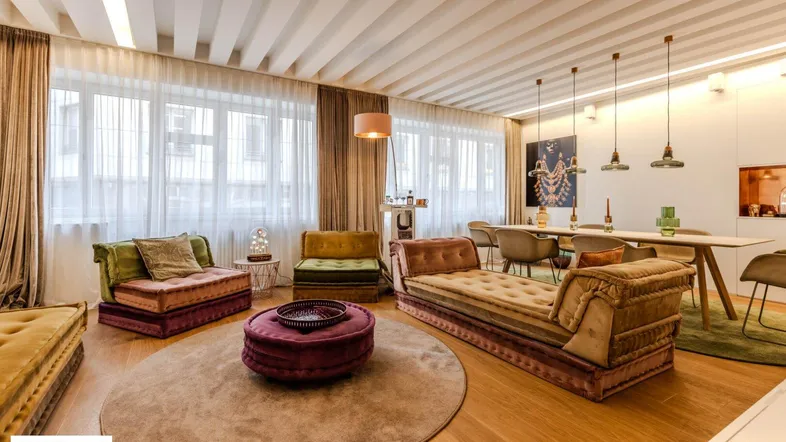 Geräumiger Wohn- und Essbereich mit stilvollen Möbeln, Holzboden und großen Fenstern.