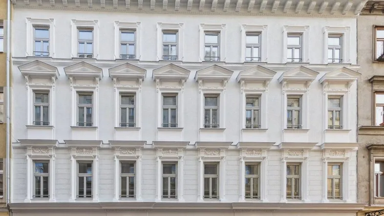 Symmetrische Ansicht der historischen Altbaufassade mit reich verzierten Fensterrahmen und Gesimsen.