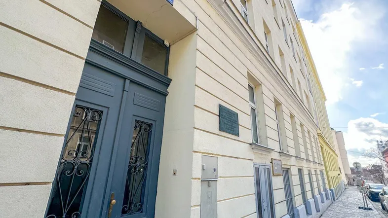 Eingangsbereich eines Altbaus mit blauer Holztür und Hausnummer 38 an einer ruhigen Straße.