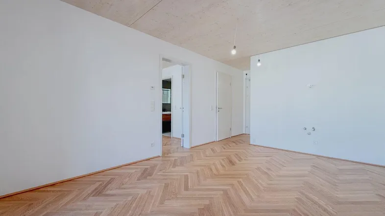 Heller Raum mit elegantem Fischgrätparkett und Holzbalkendecke, bereit zur individuellen Gestaltung.