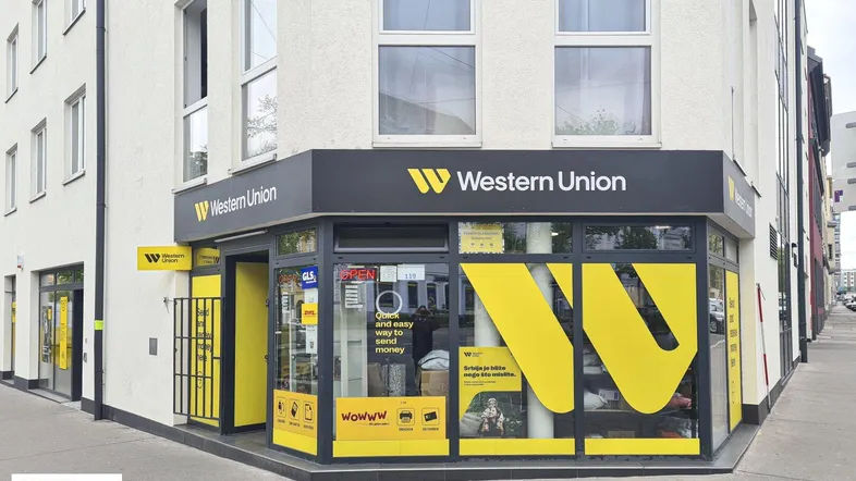 Vorderansicht eines Geschäftsgebäudes mit einer Western Union Filiale an der Ecke, gekennzeichnet durch gelbe und schwarze Beschilderung.