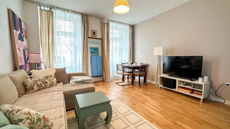 Helles Wohn- und Esszimmer mit Parkettboden, großen Fenstern und gemütlicher Einrichtung.