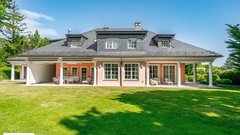 Rückansicht der eleganten Villa mit weitläufigem Garten und überdachten Terrassenbereichen.