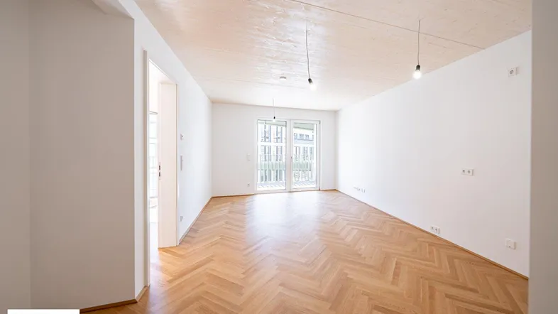Helles Wohnzimmer mit Fischgrätparkett, Holzbalkendecke und Zugang zu einem Außenbereich.