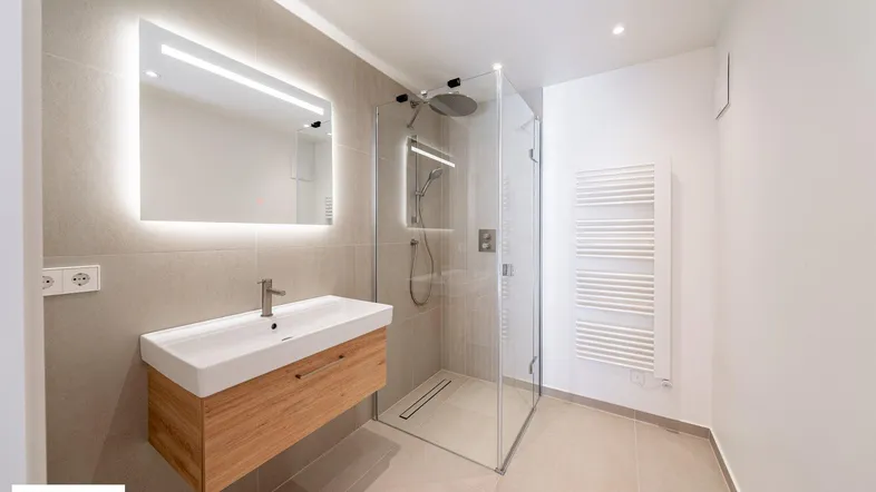 Modernes Badezimmer mit begehbarer Dusche, schwebendem Waschtisch und beheiztem Handtuchhalter.