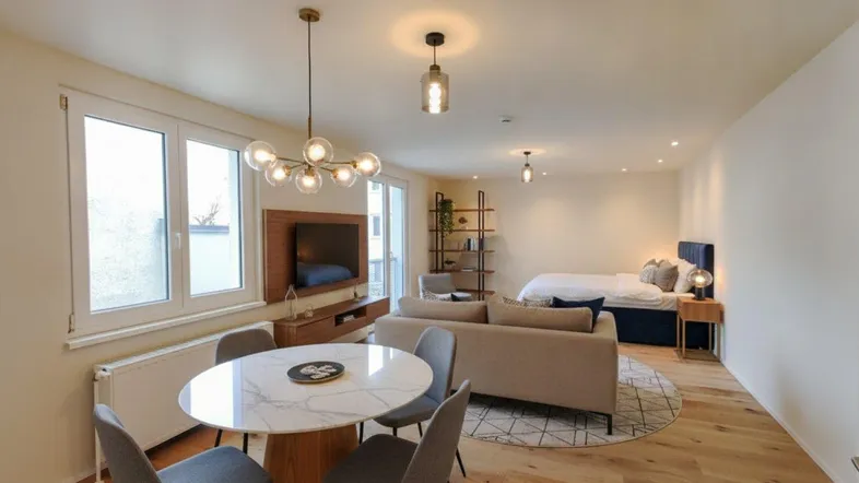 Modernes Studio-Apartment mit offenem Wohn- und Schlafbereich, hellem Parkettboden und stilvoller Einrichtung.