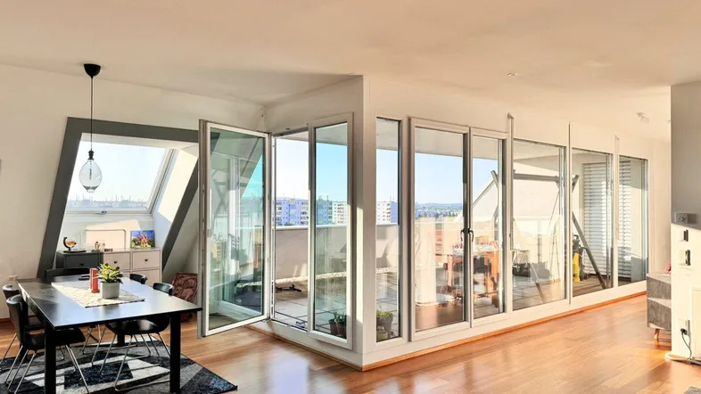 Heller Essbereich mit Holzboden, modernem Esstisch und Zugang zur Terrasse mit Stadtblick.