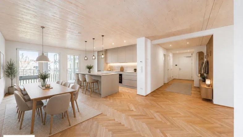 Offener Wohn-Essbereich mit integrierter Küche, Holzboden und Balkonzugang, perfekt für geselliges Beisammensein.