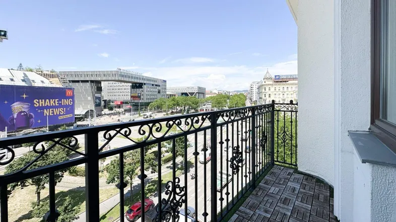 Balkon mit schmiedeeisernem Geländer und weitem Blick über die Stadt an einem sonnigen Tag.