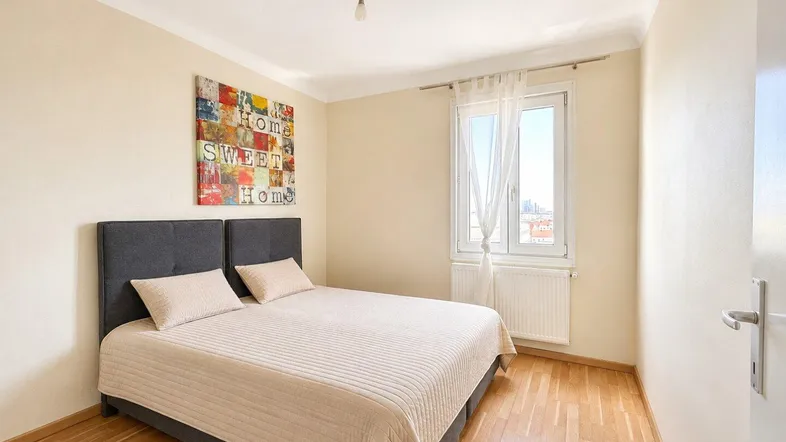 Helles Schlafzimmer mit Holzboden, einem Doppelbett und einem Fenster mit Ausblick.