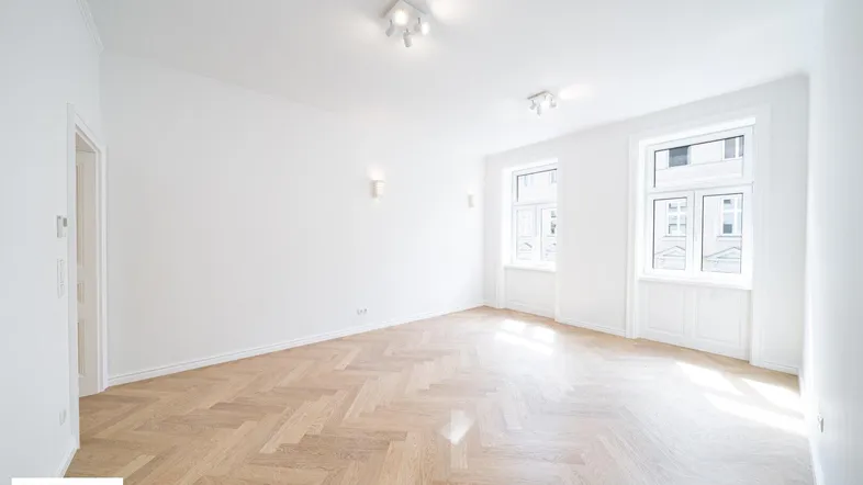 Helles Zimmer mit Fischgrätparkett und weißen Wänden, ideal als Wohn- oder Schlafbereich.