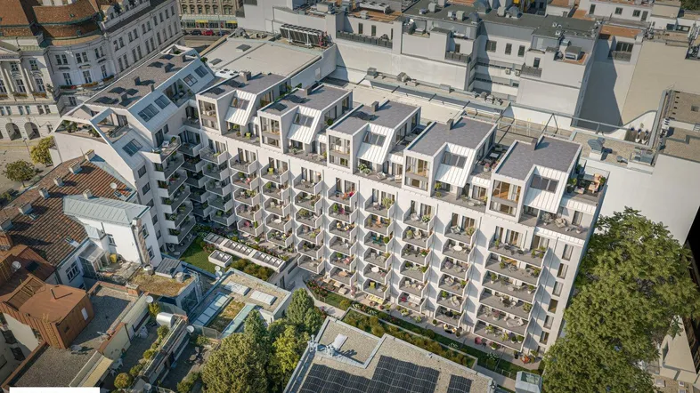 Luftaufnahme eines modernen Wohnkomplexes mit vielen Balkonen und begrünten Dachflächen in urbaner Umgebung.