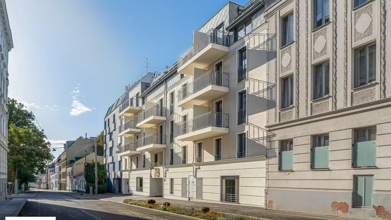 Ansicht des modernen Wohngebäudes von der Straße mit angrenzenden Altbauten und Balkonen.