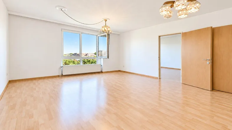 Helles Wohnzimmer mit Parkettboden, großen Fenstern und einem weiten Blick ins Grüne.