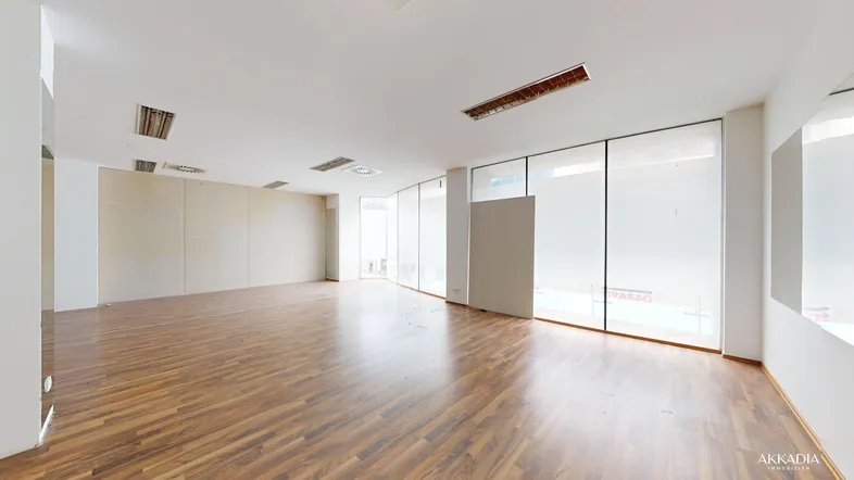 Geräumiger Büroraum mit großen Fenstern und modernem Laminatboden, ideal für gewerbliche Nutzung.