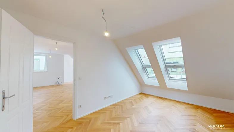 Helles Zimmer im Dachgeschoss mit Fischgrätparkett und Dachfenstern, bereit für die Einrichtung.