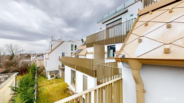 Moderne Architektur mit mehreren Balkonen und Terrassen, umgeben von Grünflächen und Bäumen.
