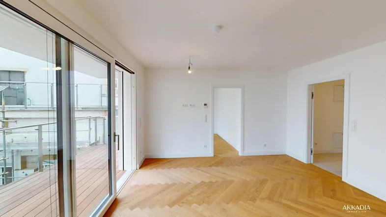 Helles Wohnzimmer mit Fischgrätparkett und großen Schiebetüren zum Balkon.
