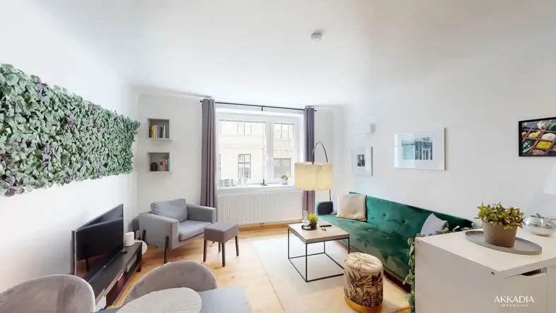 Helles Wohnzimmer mit grüner Couch, Holzboden und Blick auf die Straße.