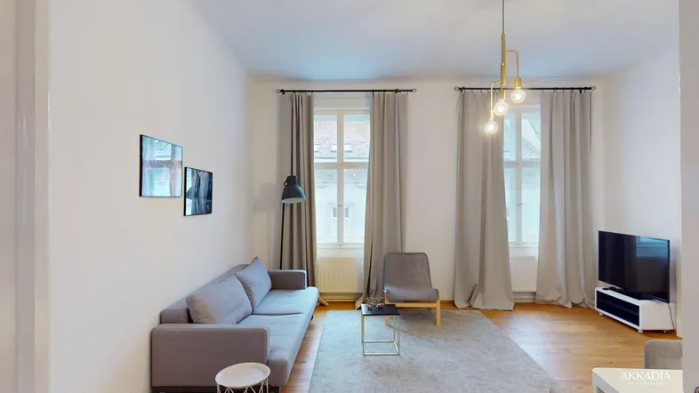 Helles Wohnzimmer mit modernem Sofa, Holzboden und großen Fenstern, die viel Tageslicht hereinlassen.