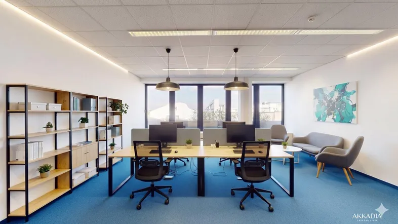 Modernes Großraumbüro mit blauer Teppichboden, ergonomischen Arbeitsplätzen und großen Fenstern mit Stadtblick.