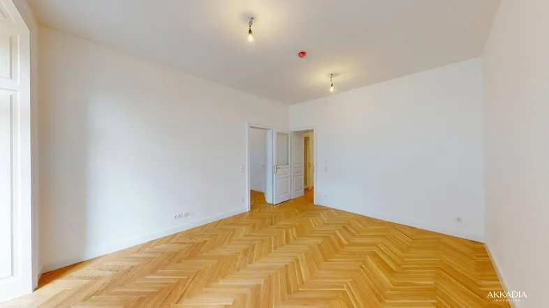 Helles, leeres Zimmer mit Fischgrätparkett und weißen Wänden, bereit zur individuellen Gestaltung.