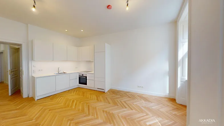 Heller offener Wohnbereich mit integrierter weißer Küche und elegantem Fischgrätparkettboden.