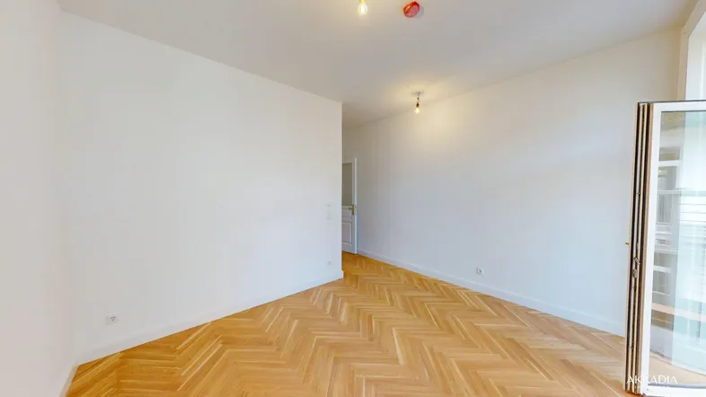 Helles Zimmer mit Fischgrätparkett und weiß gestrichenen Wänden, bereit zur individuellen Gestaltung.