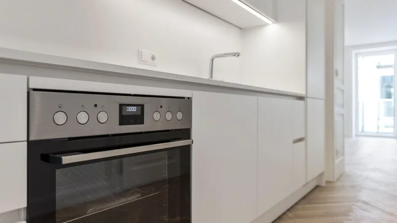 Moderne Einbauküche mit integriertem Backofen und heller Arbeitsplatte.
