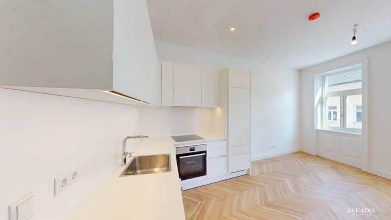 Moderne, helle Wohnküche mit weißer Einbauküche, Parkettboden und Blick nach draußen.