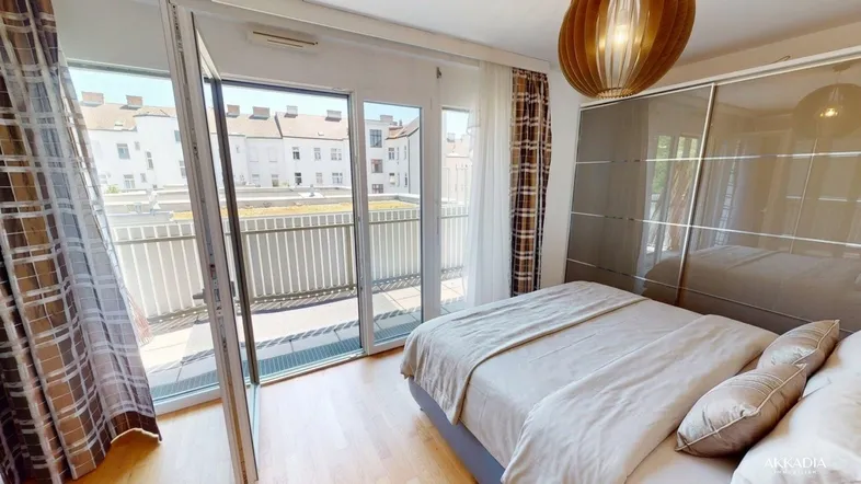 Helles Schlafzimmer mit Holzboden, großem Fenster und Zugang zu einem Balkon mit Stadtblick.