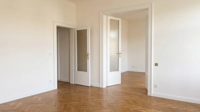 Heller Raum mit Fischgrätparkettboden und mehreren Türen, der vielseitig nutzbar ist.