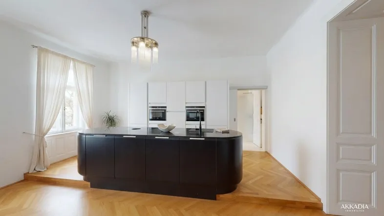 Moderne Küche mit schwarzer Kücheninsel, weißen Schränken und Fischgrätparkettboden in hellem Raum.